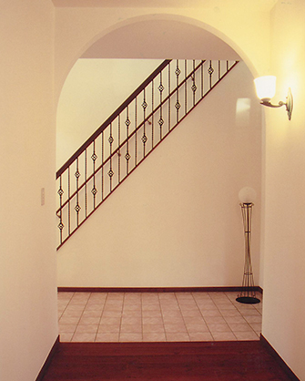 塗り壁にアーチのホールウェイ、テラコッタタイルの風合いが温もりあふれる雰囲気に。アイアンの階段手すりがアクセントになってデザイン性豊かな空間です。